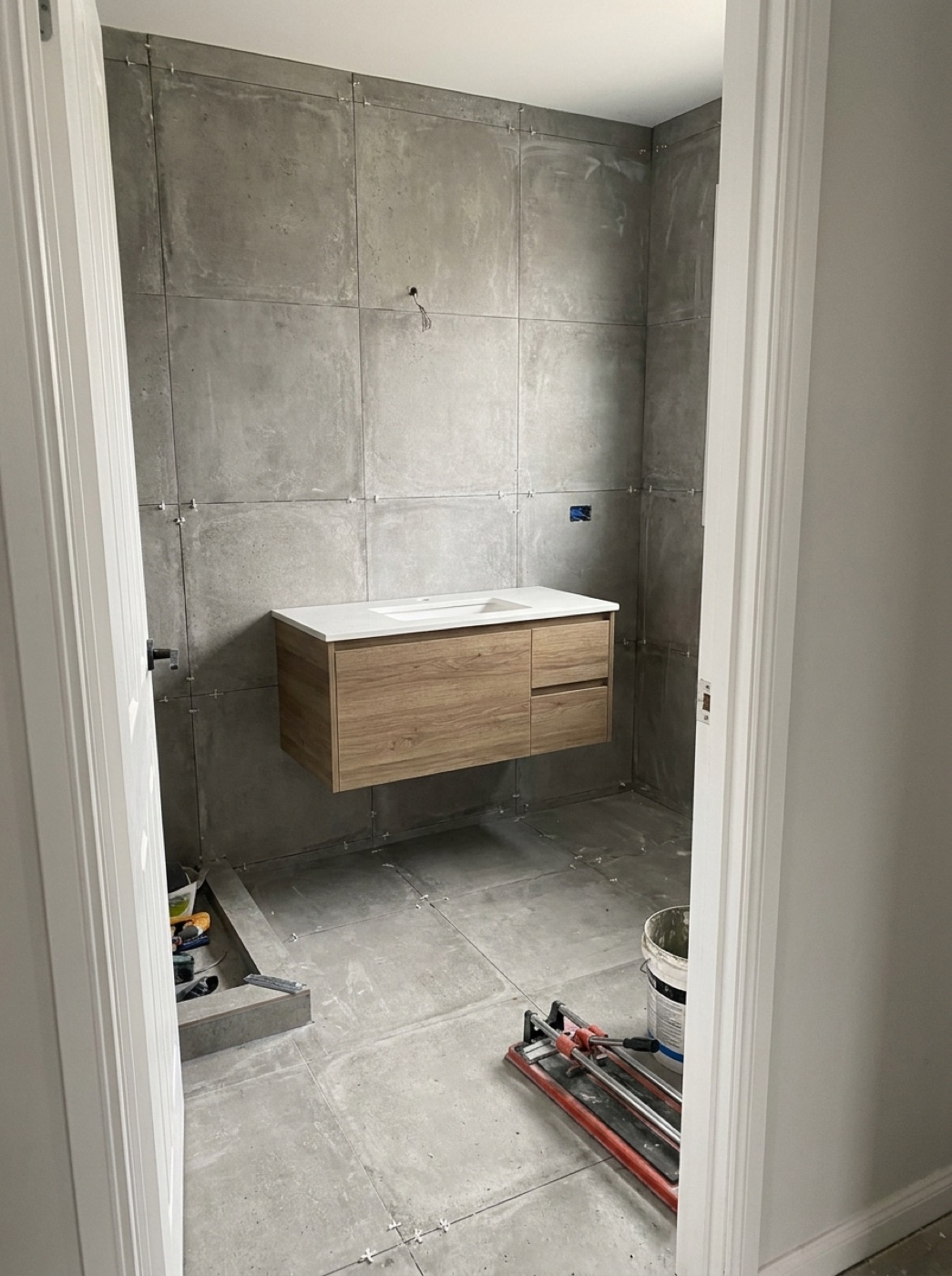 Grey concrete-look tiled ensuite with timber floating vanity