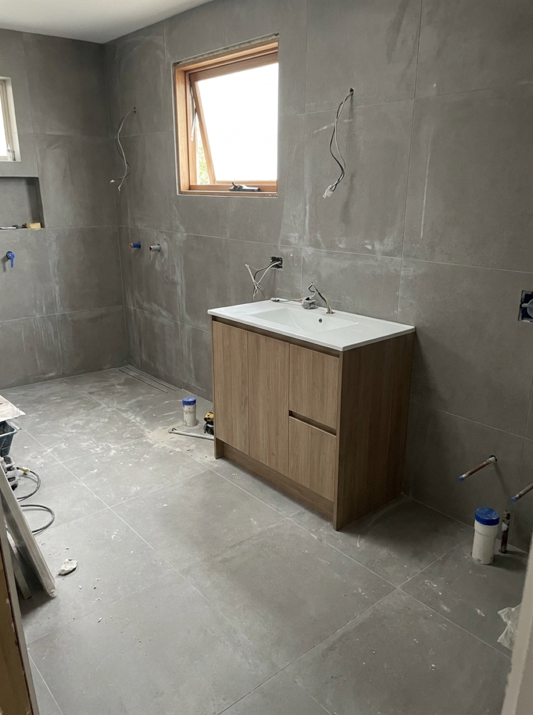 Grey large-format bathroom walls and floor with double vanity and window